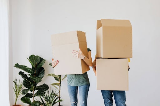 Two people carry cardboard boxes while moving house, highlighting furniture preparation for a Gold Coast move.